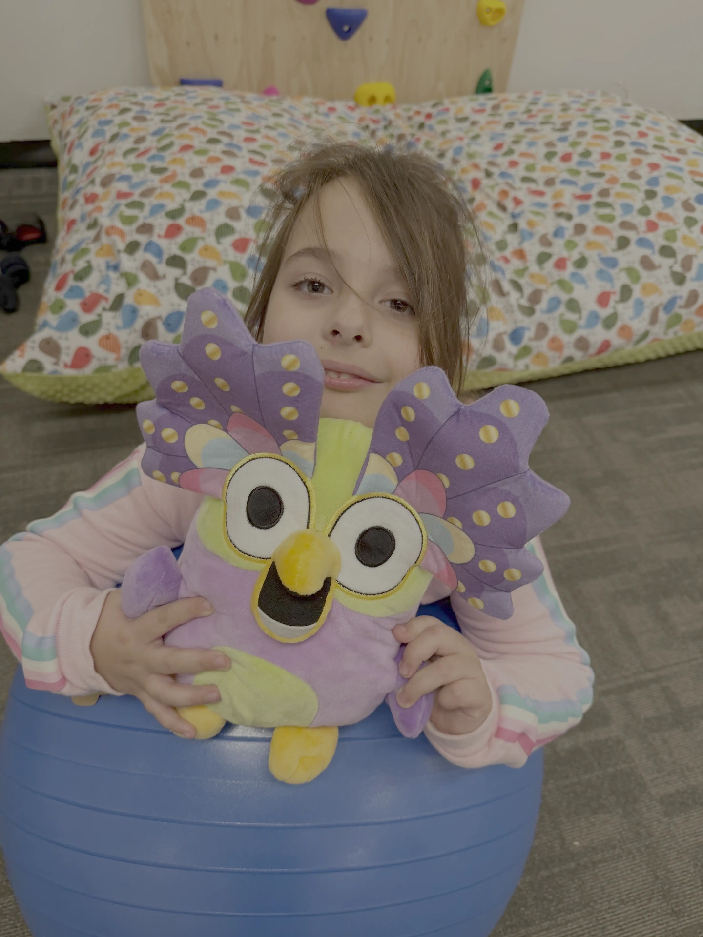 Girl with owl toy on a stability ball